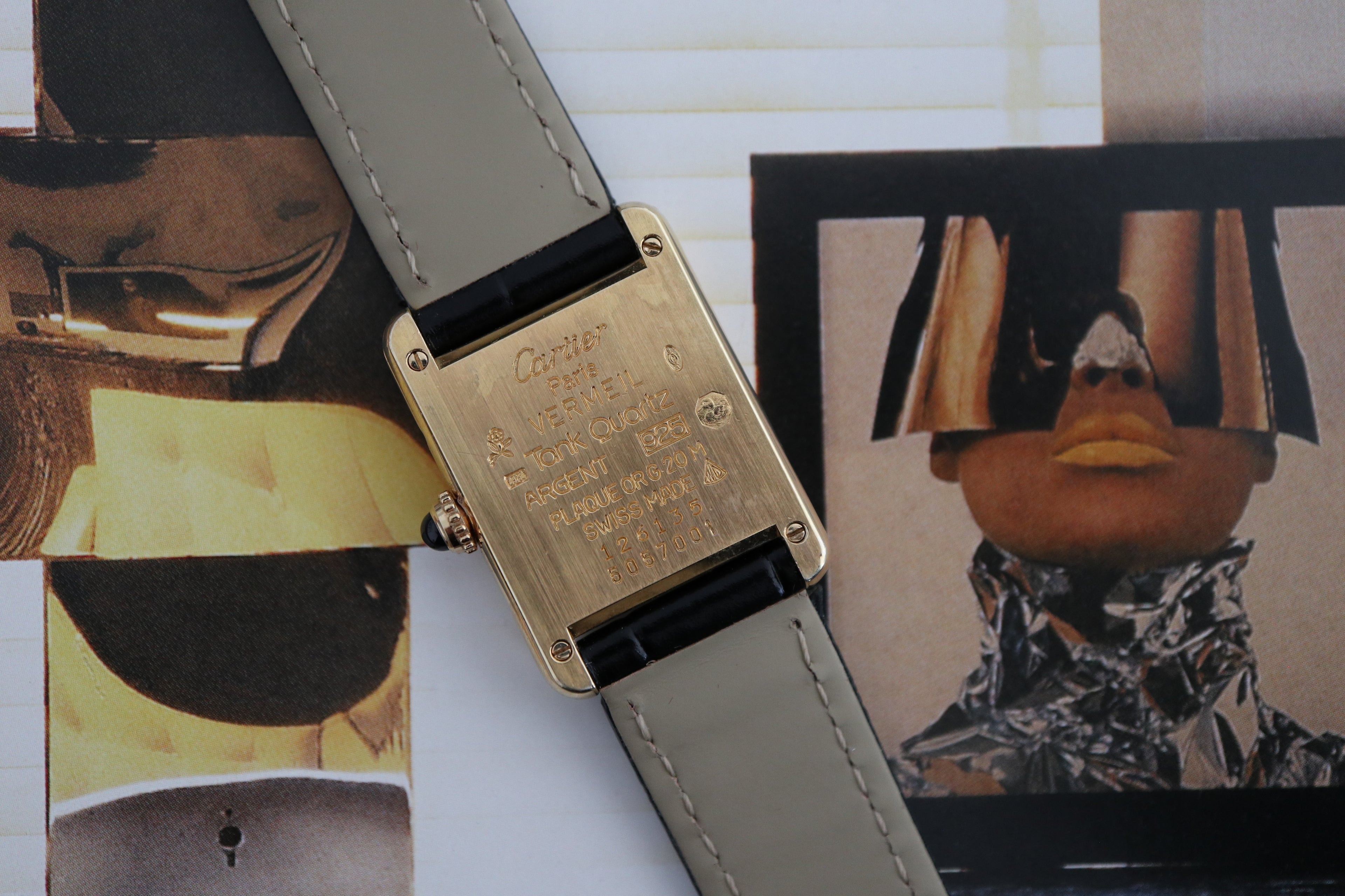 Close-up of the caseback engraving on a Cartier Tank Vermeil watch with French hallmarks and serial number, photographed against a modern editorial background.