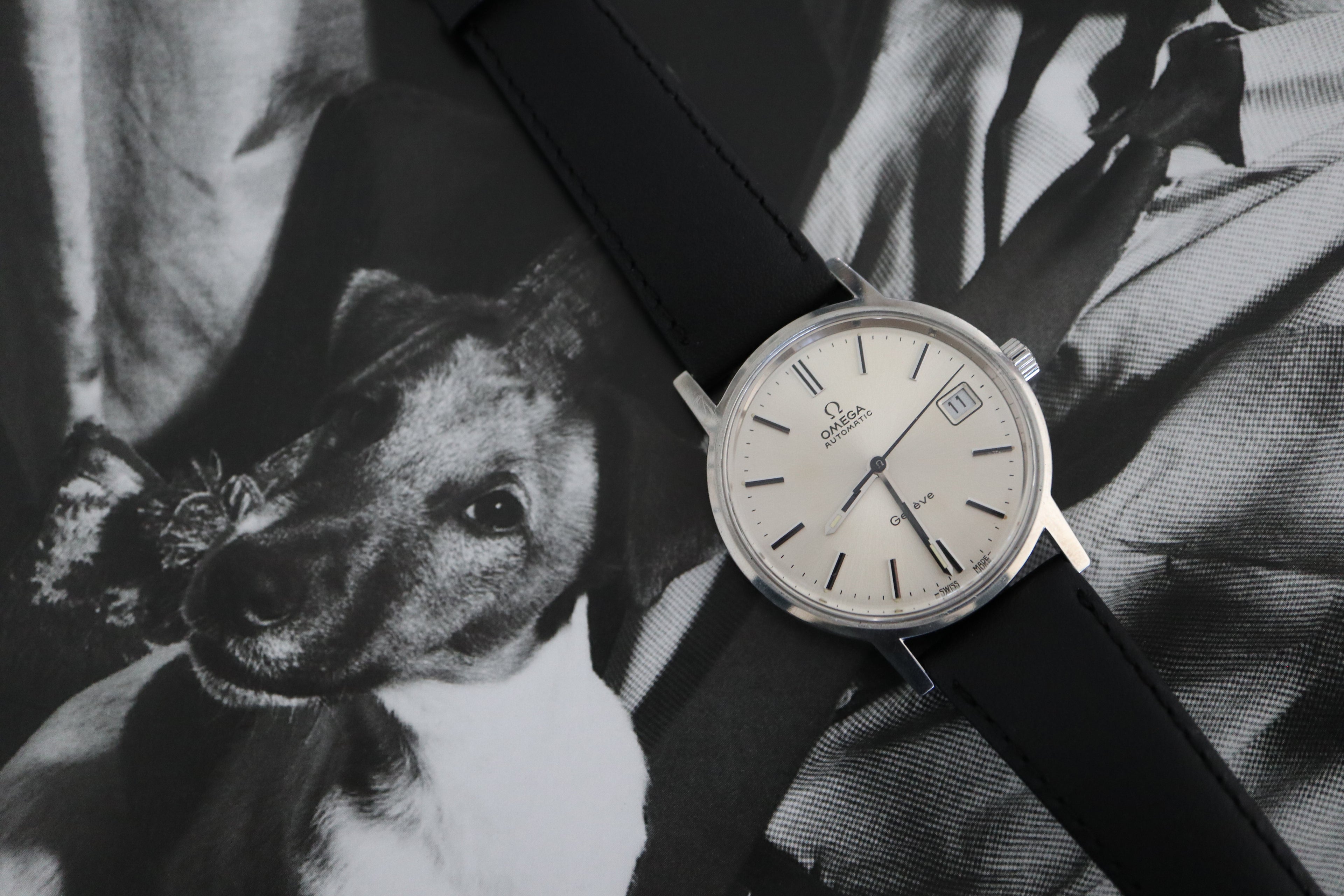 Vintage Omega Genève Automatic with silver dial, photographed against a black-and-white portrait background.